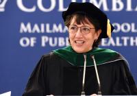 A smiling woman wearing academic regalia